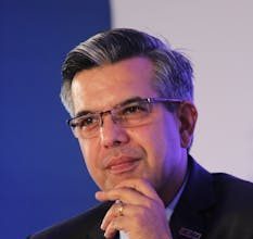 Portrait of a thoughtful businessman in a suit, wearing eyeglasses, captured in an indoor corporate setting.